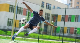 athletic soccer player kicking ball on soccer pitch during match