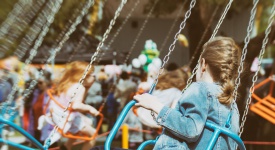 Little girl is riding a carousel in amusement park.