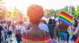 black woman holding Pride flag in a crowd