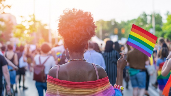 black woman holding Pride flag in a crowd